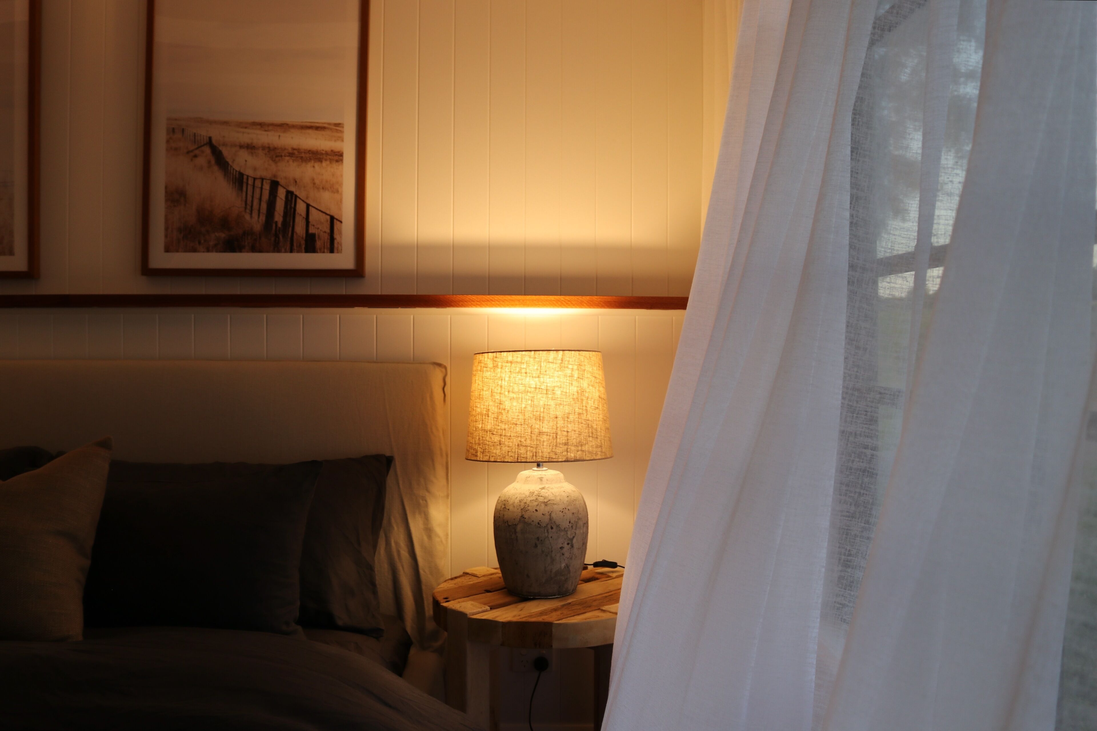 Un dormitorio con cama, una mesita de noche con lámpara y un cuadro en la pared.
