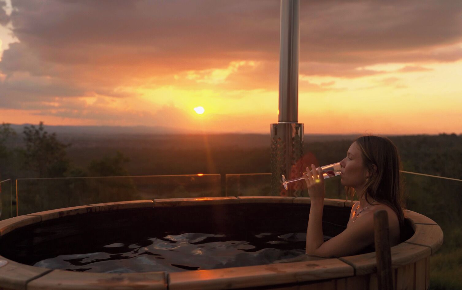 Iemand zit in een jacuzzi met uitzicht op de zonsondergang.