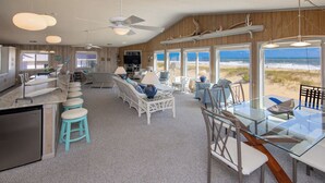 A spacious kitchen with a large island, bar stools, and a view of the beach through large windows. - Staud's Stilts - Oceanfront home w/pool and direct beach access (Virginia Beach)