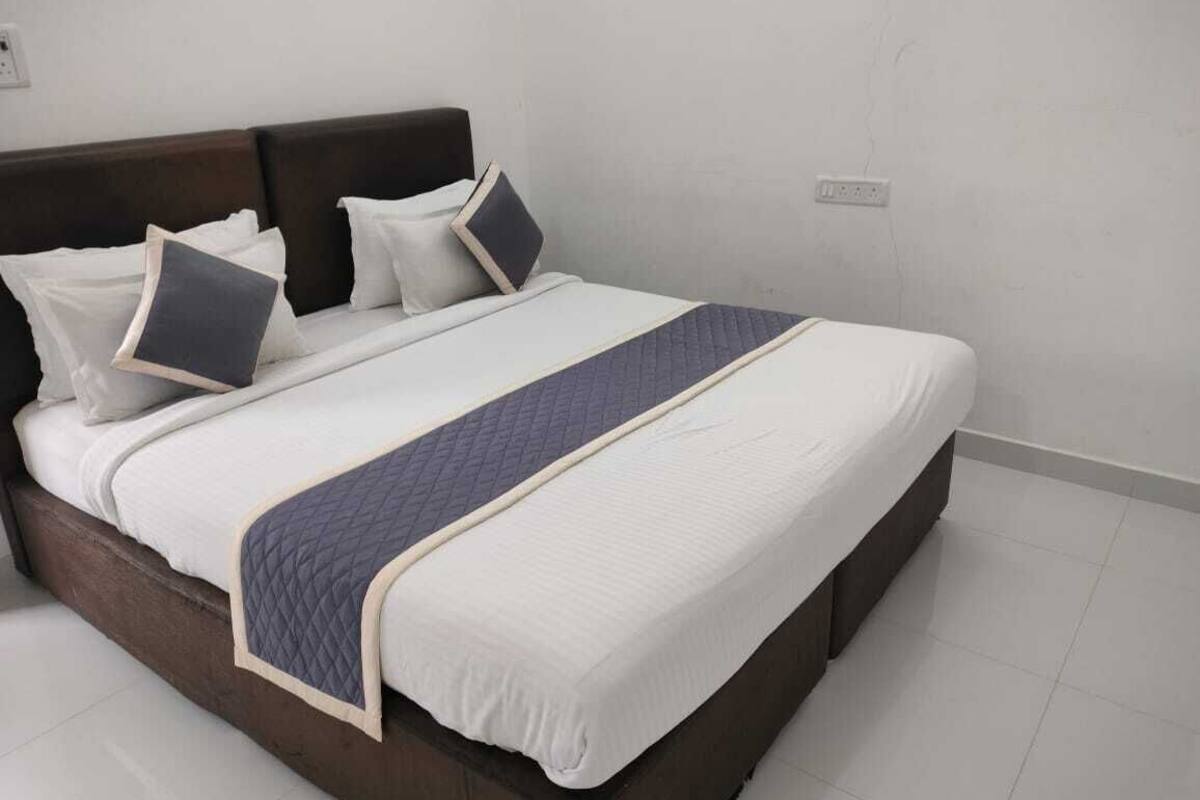Ein ordentlich gemachtes Bett mit dunklem Kopfteil, weißer Bettwäsche und blauem Akzent.