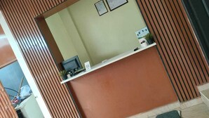 A reception desk with a green wall, two framed certificates, and a small plant on a shelf. - Eben Service Apartment  (Chennai)