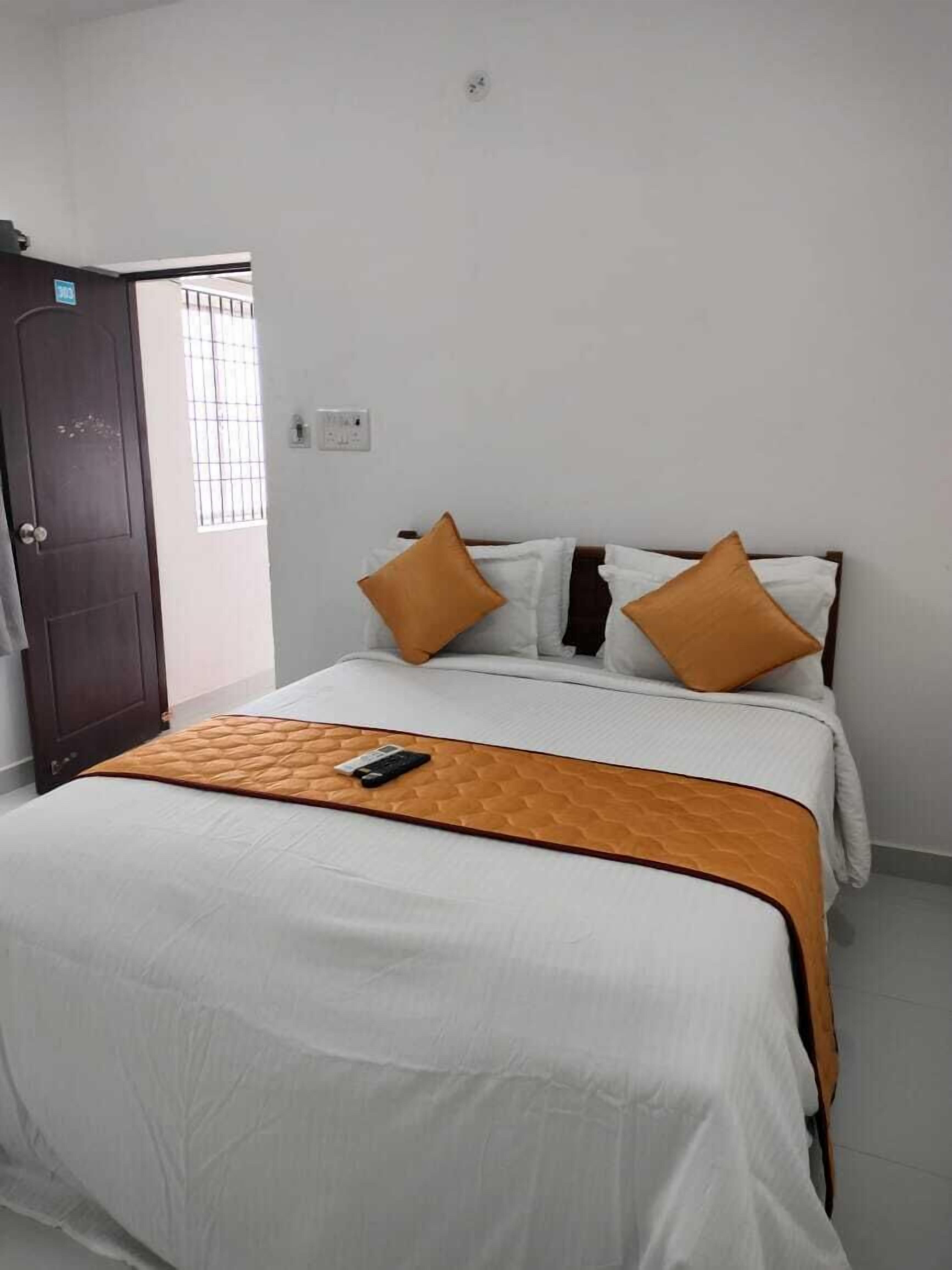A bedroom with a bed, a wooden door, and a window.