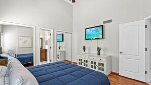 Ein Schlafzimmer mit einem großen Bett, einem an der Wand montierten Fernseher und einem Kleiderschrank.