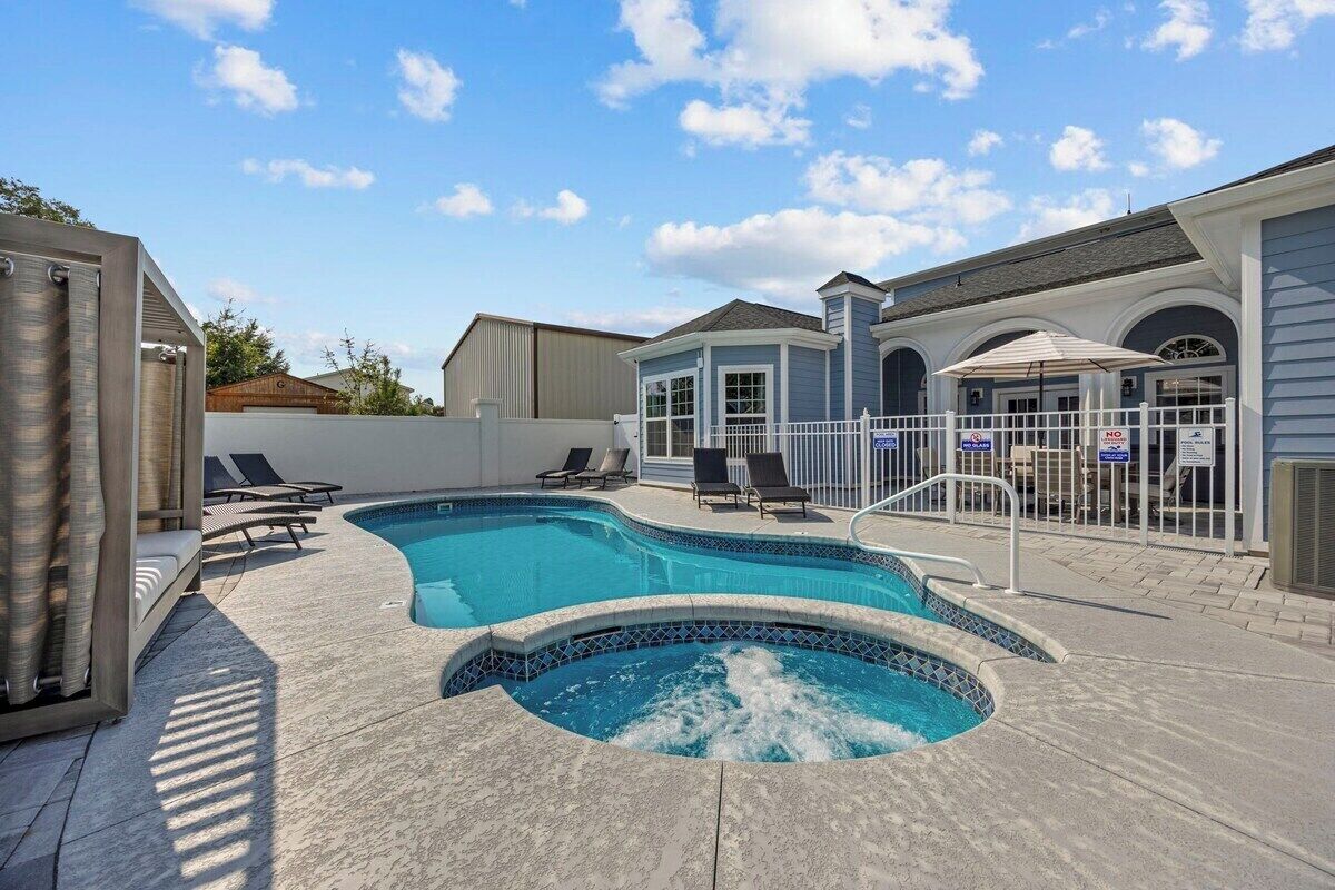 Une piscine avec des chaises longues, un jacuzzi et un patio clos.