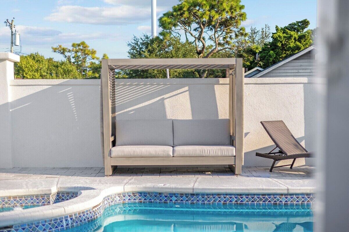 A pool area with a sunbed and a lounge chair.