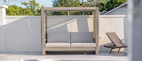 A pool area with a sunbed and a lounge chair.