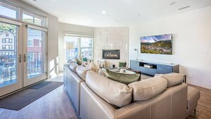 Ein modernes Wohnzimmer mit Ledersofa, Kamin und großem Fernseher an der Wand.