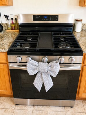 Una cocina con estufa de acero inoxidable, un reloj digital y un lazo decorativo en la puerta del horno.