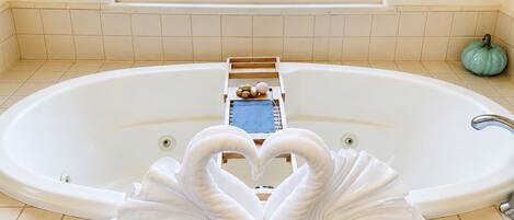 Ein Badezimmer mit einer großen Badewanne, einem Fenster und einer dekorativen Handtuchgestaltung mit dem Motiv eines Schwans.
