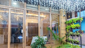 A building entrance with glass doors, potted plants, and string lights. - Grace Apart Hotel (Kanayannur)