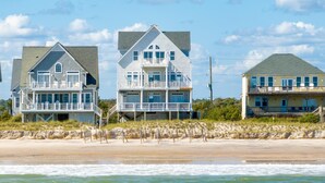 Three beachfront houses with multiple stories and balconies, situated on a sandy beach with ocean waves in the foreground. - Oceanfront 7BR Sleeps 21 Hot Tub, Comm. Pool, 15 steps to the beach, 360 Views! (North Topsail Beach)