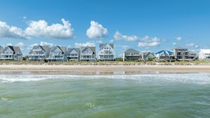 A beachfront property with multiple houses along the shore, featuring balconies and a sandy beach in the foreground. - Oceanfront 7BR Sleeps 21 Hot Tub, Comm. Pool, 15 steps to the beach, 360 Views! (North Topsail Beach)