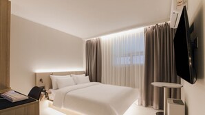 A modern hotel room with a large bed, a desk with a computer, a TV mounted on the wall, and a window with curtains. - Hwagok August (Seoul)