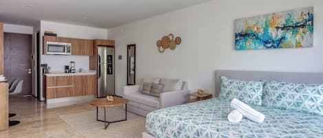 A modern living room with a sofa, a coffee table, and a bed with a geometric patterned duvet.