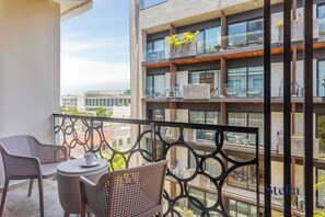 A balcony with wicker furniture and a view of a multi-story building.