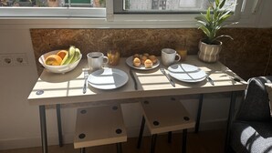 Una cocina con ventana, una mesa lista para el desayuno y una planta en maceta.