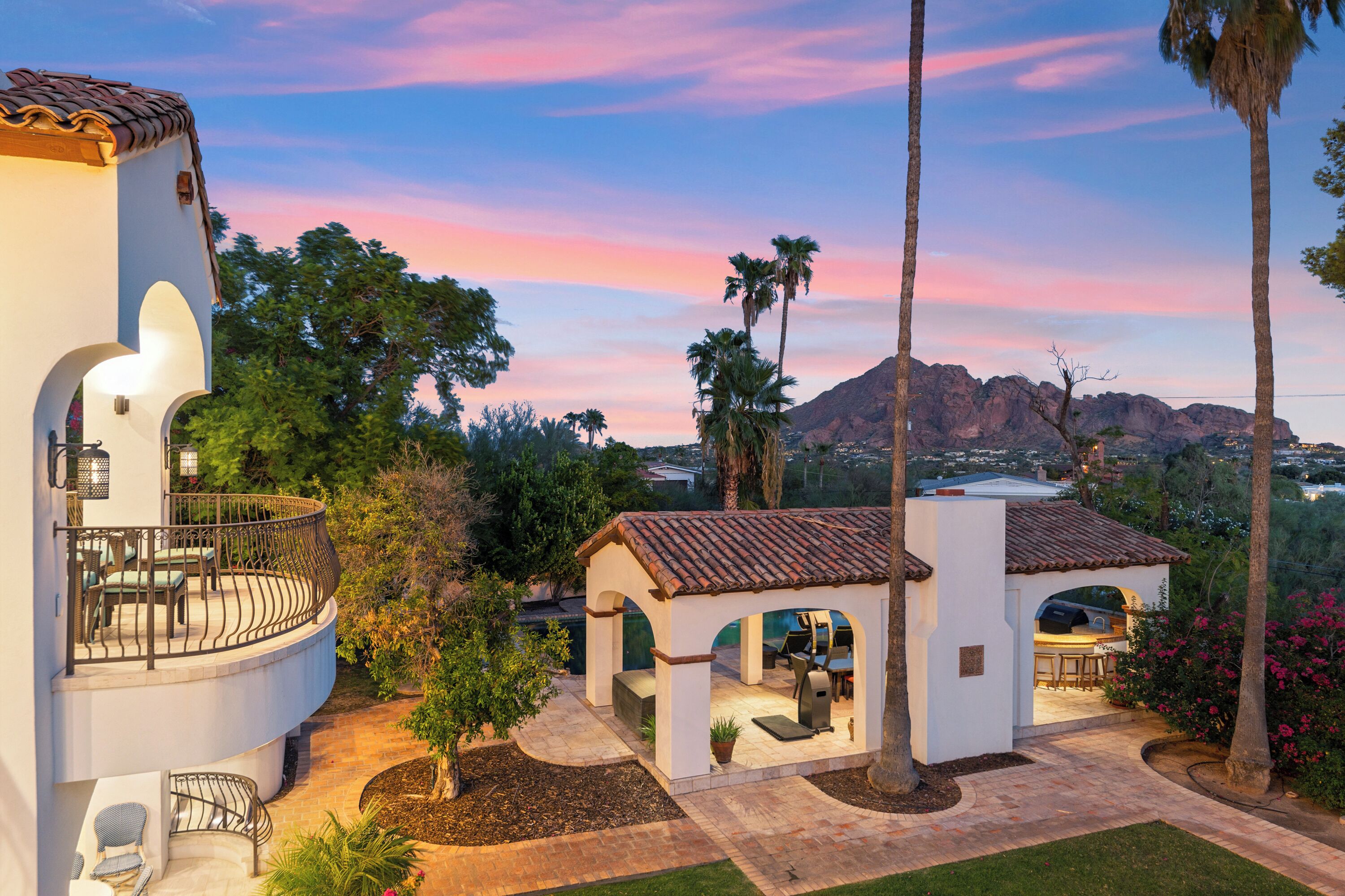 A multi-level house with outdoor seating areas, a barbecue, and a view of a mountain and lake.