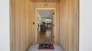Een houten gang inpandig, leidend naar een moderne keuken met een centraal eiland.