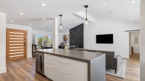 Een moderne keuken met een centraal eiland, een houten schuifdeur en een zithoek met een bank.