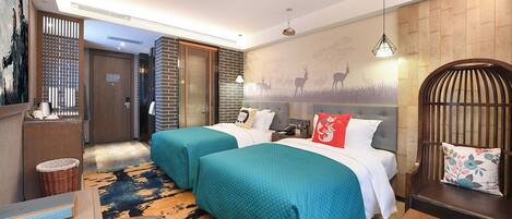 A hotel room with two beds, a wooden chair, a small table, a basket, and a wall with a deer mural.
