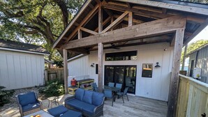 A covered patio with wicker furniture, a fire pit, and a barbecue grill.