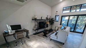 A modern living room with a flat-screen TV, a sofa, a coffee table, and a fireplace.