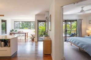 A modern room with a bed, a dining area, and a view of greenery.