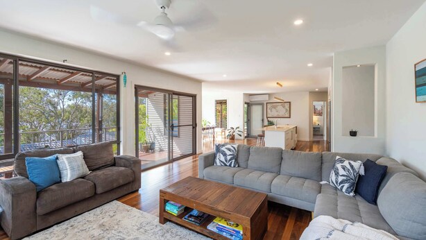 A spacious living area with a large sofa, a coffee table, and a sliding glass door leading to an outdoor patio.