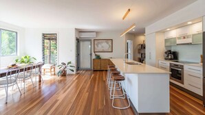 A modern kitchen with a central island, bar stools, and a dining area with a wooden table and chairs.