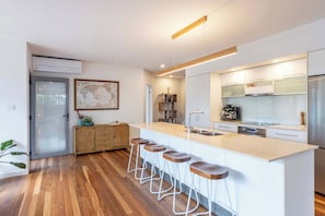 A modern kitchen with a large island, bar stools, and a world map on the wall.