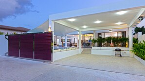 Une maison moderne dotée d’un patio couvert, d’une piscine et d’un espace repas.