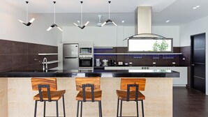 Une cuisine moderne dotée d’un îlot central, de tabourets de bar et de luminaires suspendus.