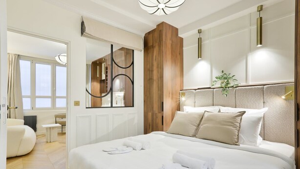 Ein modernes Hotelzimmer mit einem großen Bett, einer Wandvertäfelung aus Holz und Blick auf die Stadt.