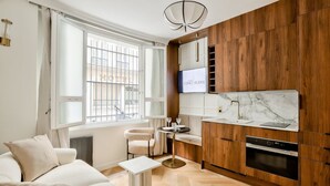 Ein modernes Hotelzimmer mit einer Holzküche, einer Couch, einem kleinen Tisch und einem Fernseher.