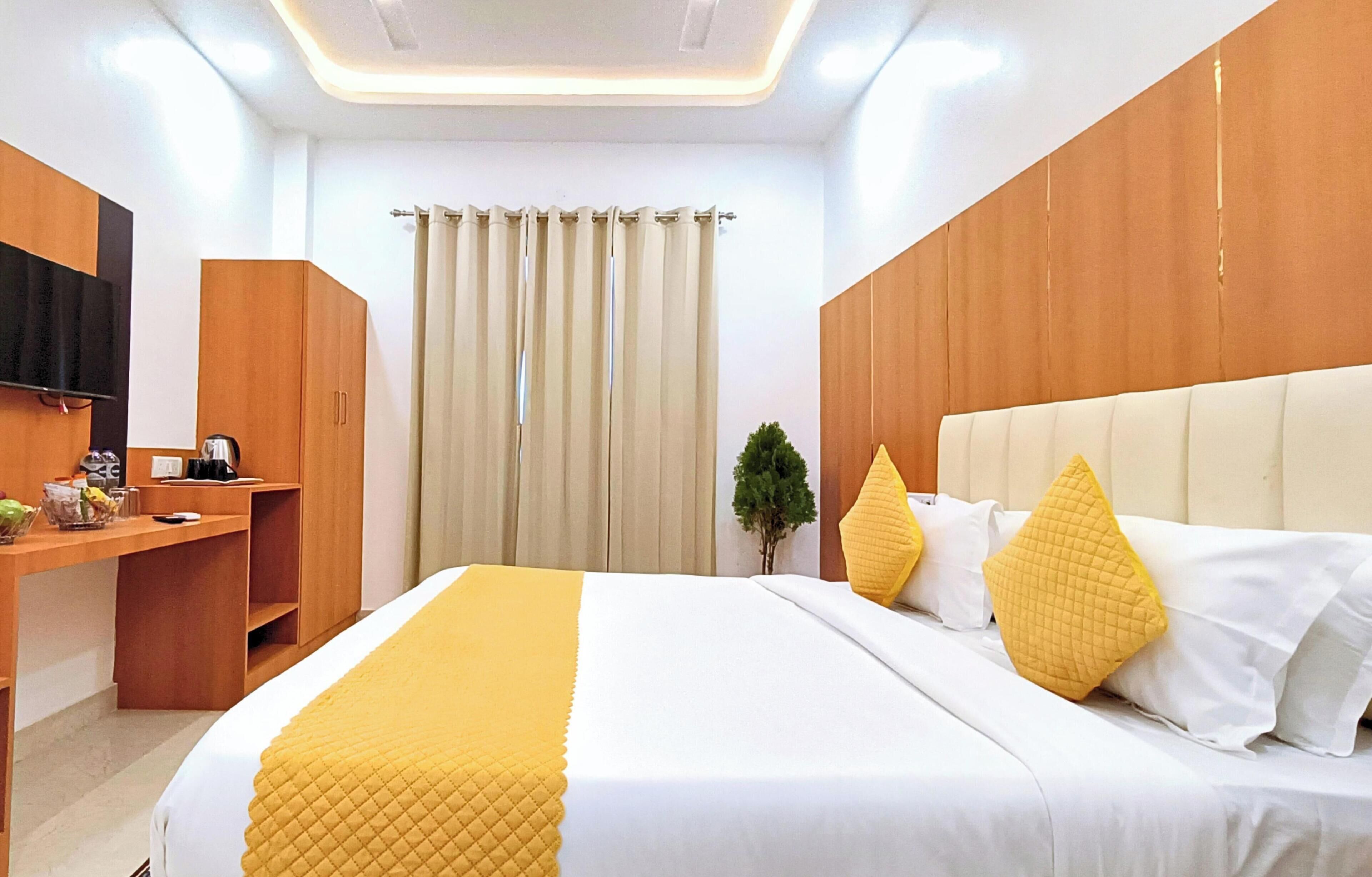 A hotel room with a bed, a desk, a television, and a window with curtains.