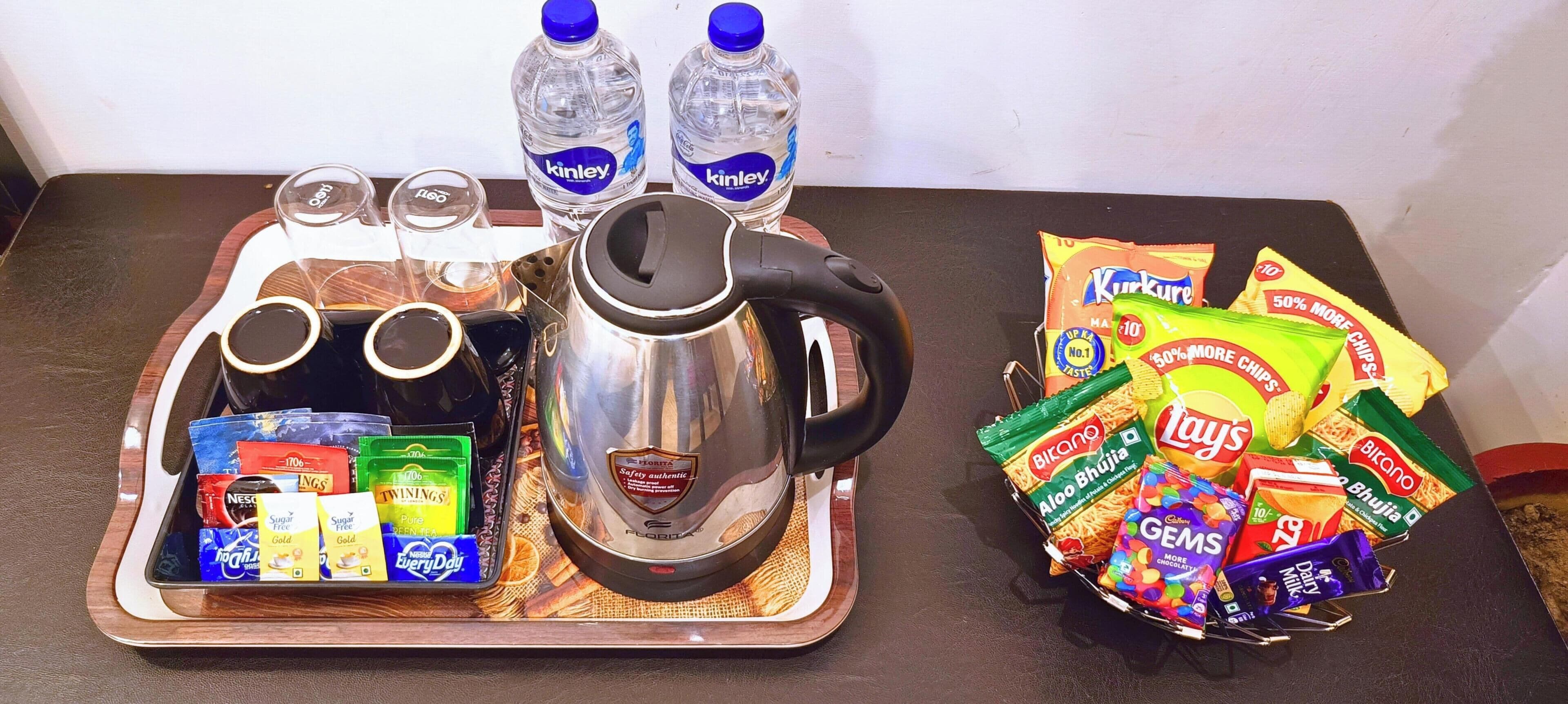 En bakke med kaffepotte, vandflasker og snackposer.