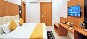 Ein Hotelzimmer mit einem Bett, einem Fernseher, einem Schreibtisch mit Snacks und einer Tür.