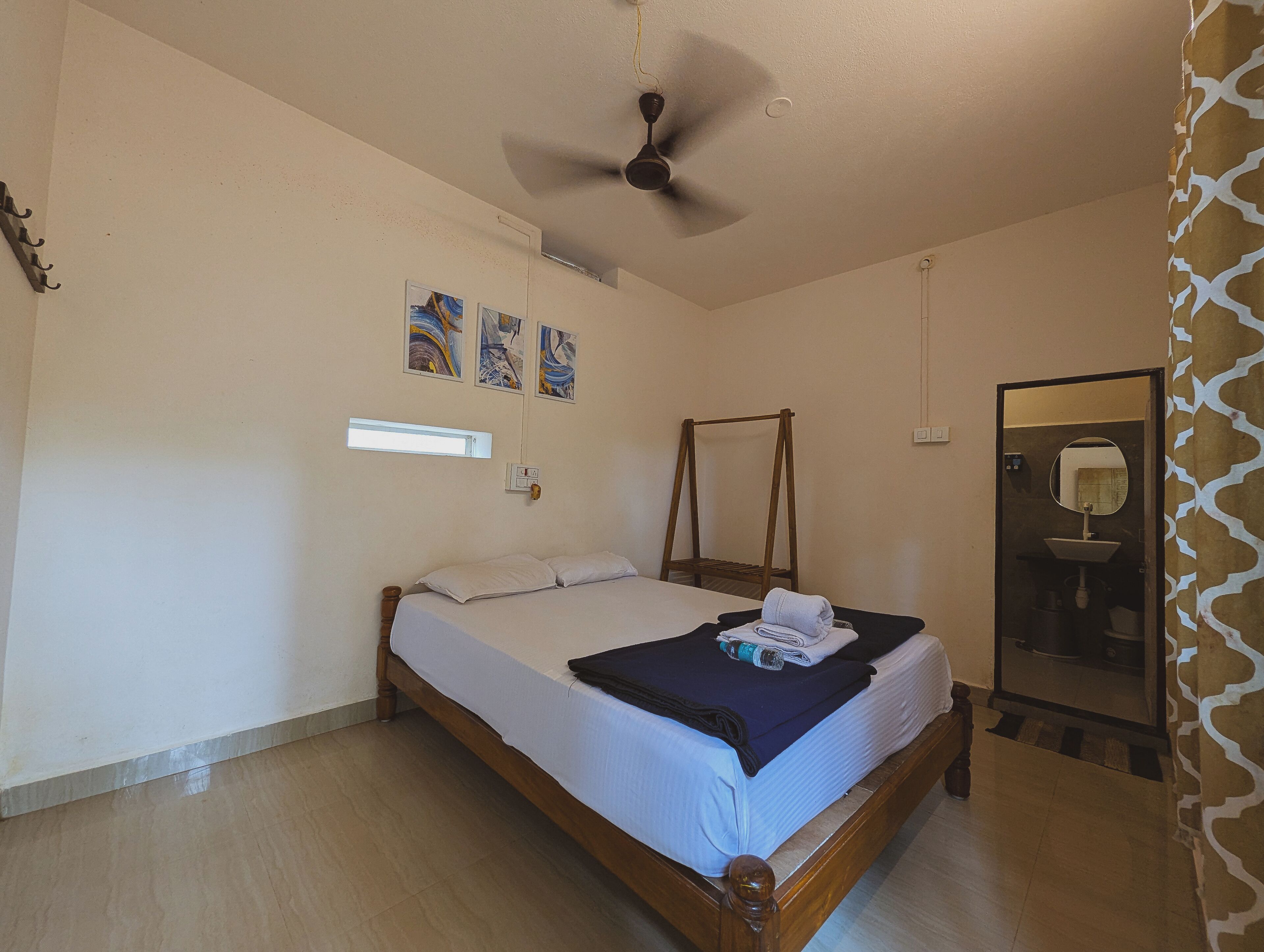 A bedroom with a bed, a ceiling fan, a wall-mounted light, and a mirror above the door.