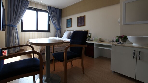 Una habitación de hotel con una cama, una mesa redonda, dos sillas, un escritorio y un armario.