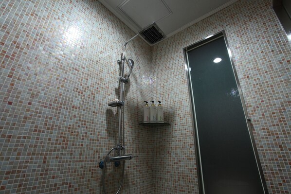 A bathroom with a tiled shower area, a door, and a shelf with toiletries. - Seocho Yuwon Hotel Nambu Terminal (Seoul)