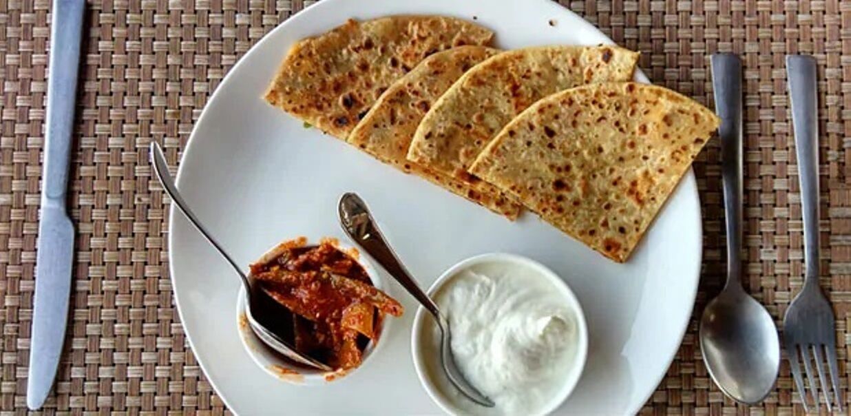 A plate with three pieces of flatbread, a small bowl of red sauce, and a small bowl of white sauce.