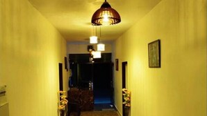 A narrow hallway with a patterned carpet, a hanging pendant light, and a door at the end. - Burans Breeze A Home Away From Home (Dhanaulti)