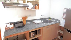 A compact kitchen with a built-in microwave, a sink, and a stove. - Davao Condo 2BR Unit Pool Wi-Fi Netflix (Davao)