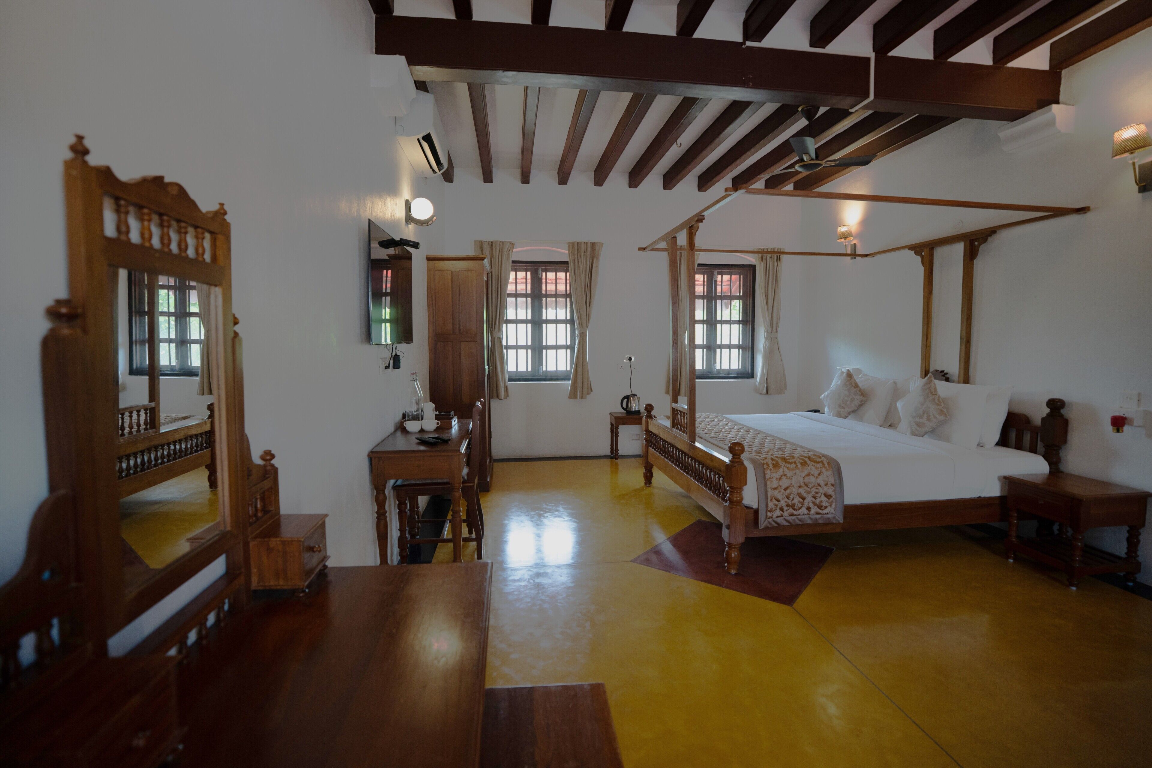 Una habitación tradicional con cama con dosel, muebles de madera y un espejo grande.