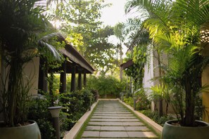 Um caminho ladeado por vasos de plantas e uma construção tradicional com telhado de telhas.