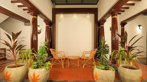 A lobby with a central seating area, wooden columns, and potted plants. - FRANCO TAMIL VILLAS (Puducherry)