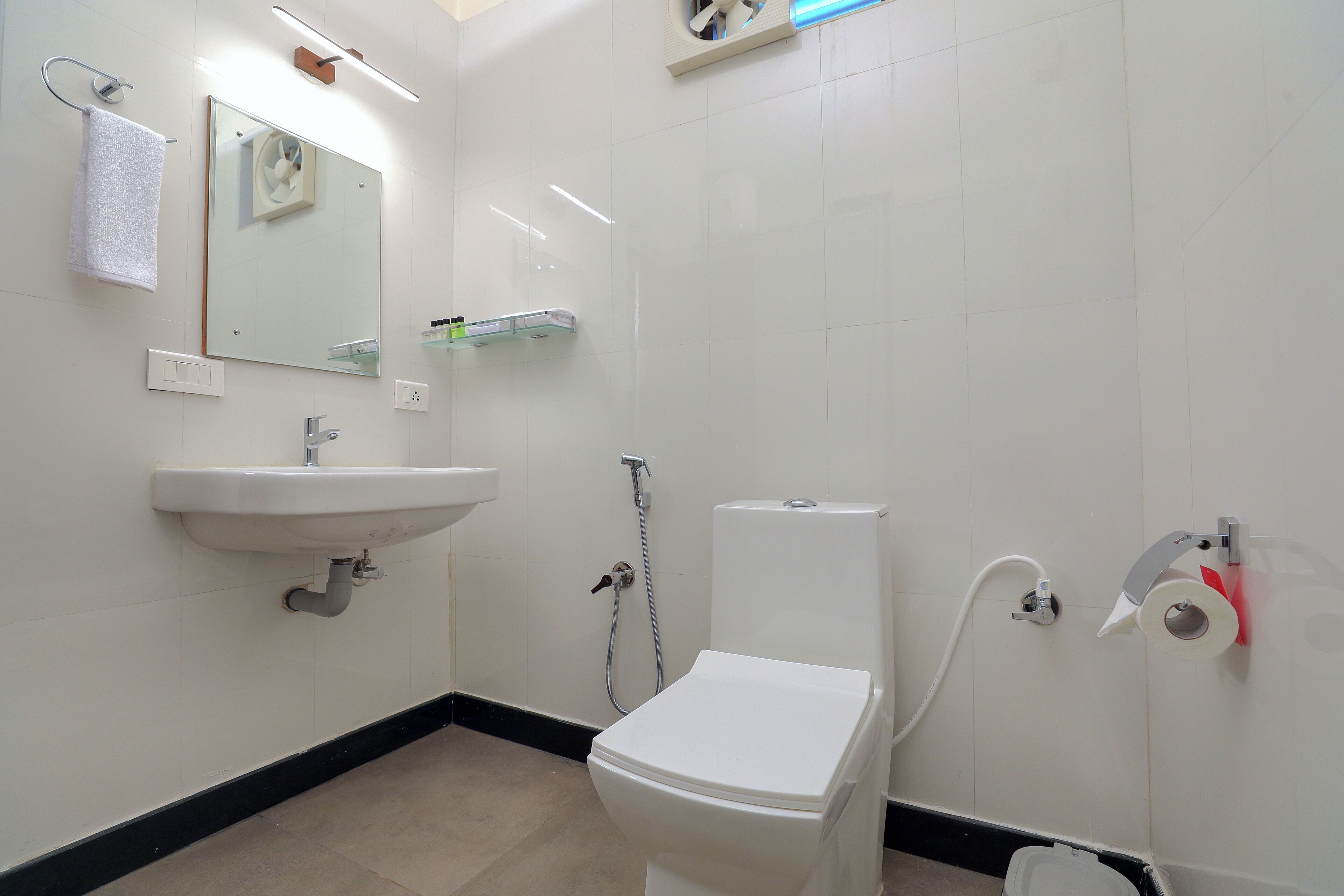 Un baño con inodoro, lavamanos y espejo.