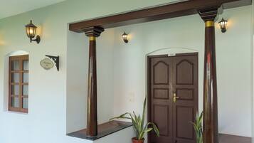 A wooden door with a number plate, a potted plant, and a bench.