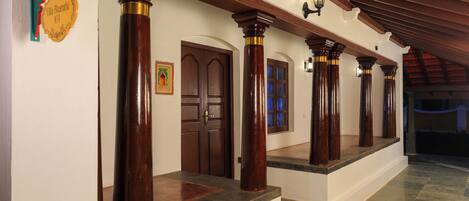 A corridor with wooden columns, a door, and a staircase.