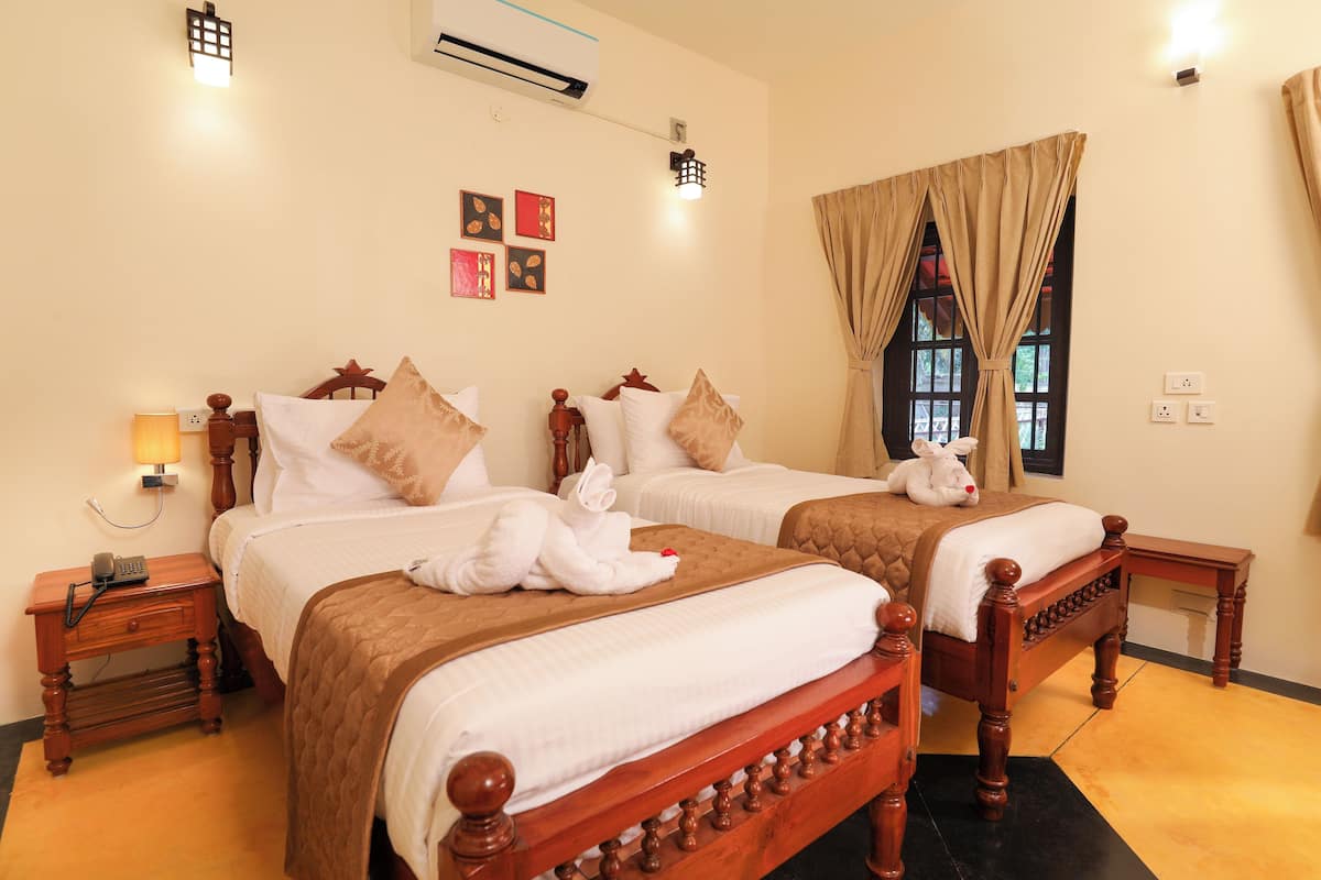 A hotel room with two wooden beds, a nightstand with a lamp, and a window with curtains.